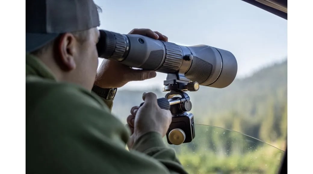 A Man Using the Leupold Optics Window Mount Clamped to Car Glass Window with Spotting Scope
