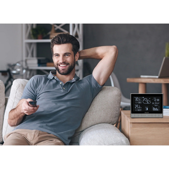 Explore Scientific CrystalVision Advanced Weather Station with LED Touch Keys Beside a Man Indoors